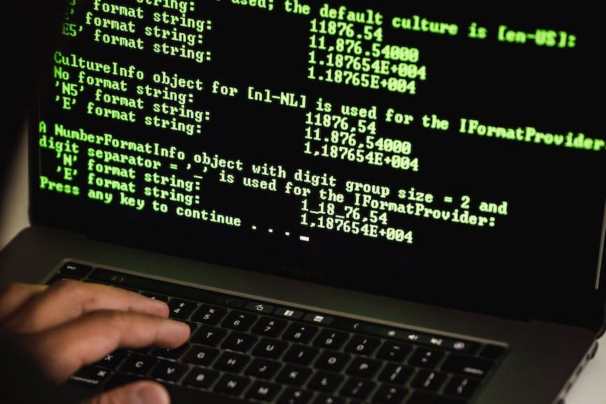 crop hacker typing on laptop with data on screen